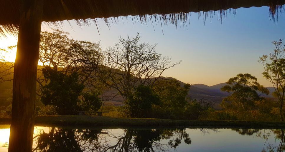 Enjoy a sun-downer walk to the dam at Wide Horizons Nature Reserve in Eswatini, featuring a scenic view of the setting sun over grassy plains